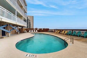 A pool with a 5½ FT depth limit, surrounded by outdoor seating and a building with balconies. - Oceanview condo with pool, private balcony & direct beach access (Murrells Inlet)