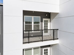 Un bâtiment moderne doté d’un balcon agrémenté d’une rambarde en métal noir.
