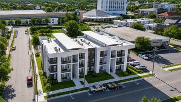 A multi-story hotel with a central courtyard, parking lot, and a view of surrounding buildings.