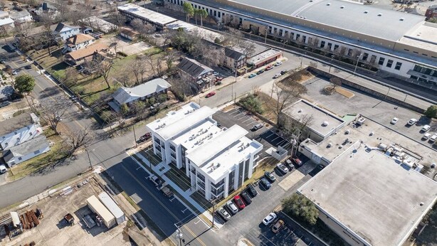 An aerial view of a commercial area with a large building, parking lots, and a train station. - Stylish 1 BR Suite • Downtown • Convention Center (Hot Springs)