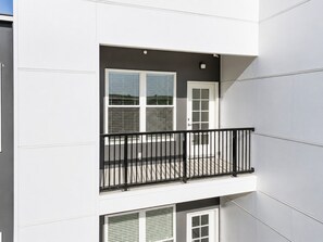 A multi-story building with a balcony, a door, and windows. - Stylish 1 Bed Suite • Downtown • Convention Center (Hot Springs)