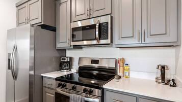 A modern kitchen with stainless steel appliances, including a refrigerator, microwave, stove, and oven.