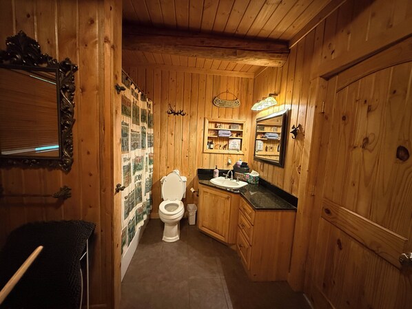 Un baño de madera con inodoro, lavamanos y espejo.