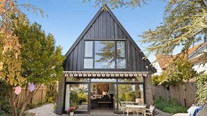 A modern house with a triangular roof, large windows, and a patio with outdoor furniture. - Beautiful home in Greve with WiFi (Greve)