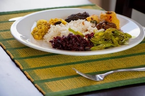 Un plato de comida con arroz, verduras y un guiso de carne.