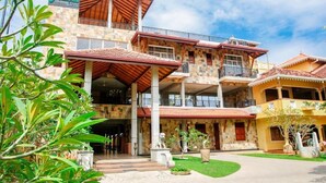 A multi-story hotel with a stone facade, balconies, and a covered entrance. - jasmin villa ayurveda resort (Negombo)