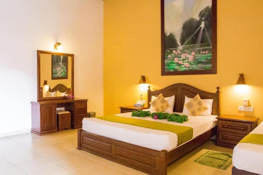 A hotel room with a large bed, a dresser, a mirror, and a painting on the wall.