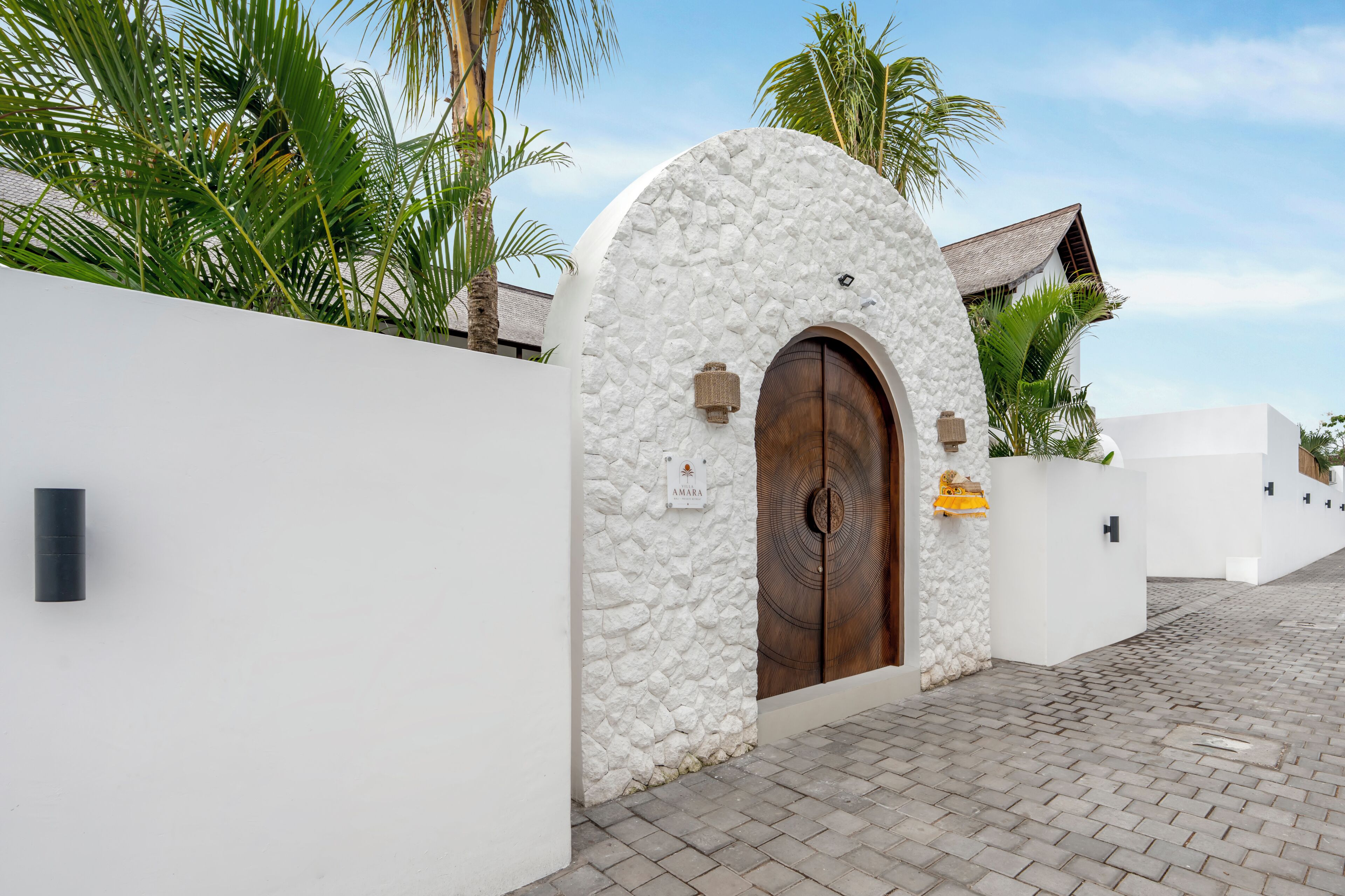 Un muro de piedra blanca con una puerta de madera y un letrero.