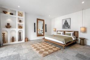 Ein Schlafzimmer mit einem Bett, einem großen Spiegel, einem Wandbild und einer Ablage mit Dekoration.