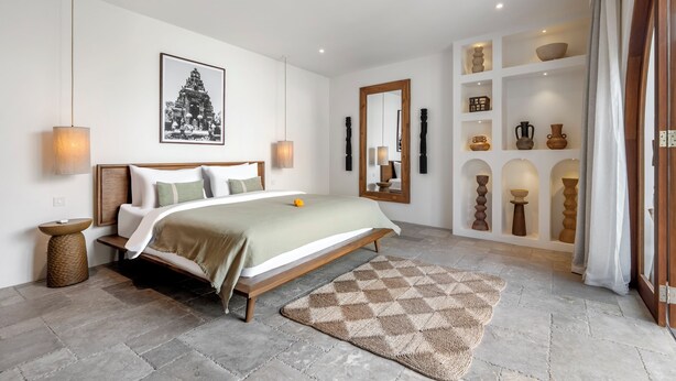 Een moderne slaapkamer met een bed, nachtkastjes, een grote spiegel en een wandplank met decoratieve objecten.