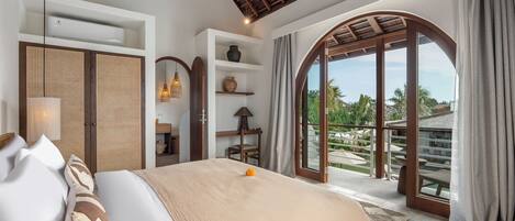 Un dormitorio con una cama grande, un armario, estanterías y vistas a un jardín a través de un ventanal.