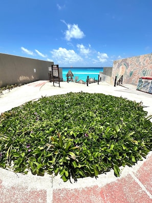 Una zona de playa con un jardín circular, un mural y un cartel.