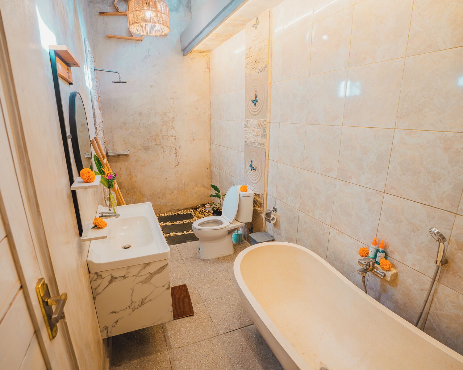 A bathroom with a bathtub, toilet, and sink, marble walls, and a shower area.