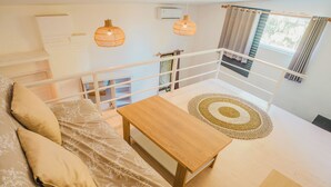 Ein Schlafzimmer mit einem Bett, einem Holztisch, einem Teppich und einem Balkon mit Geländer.