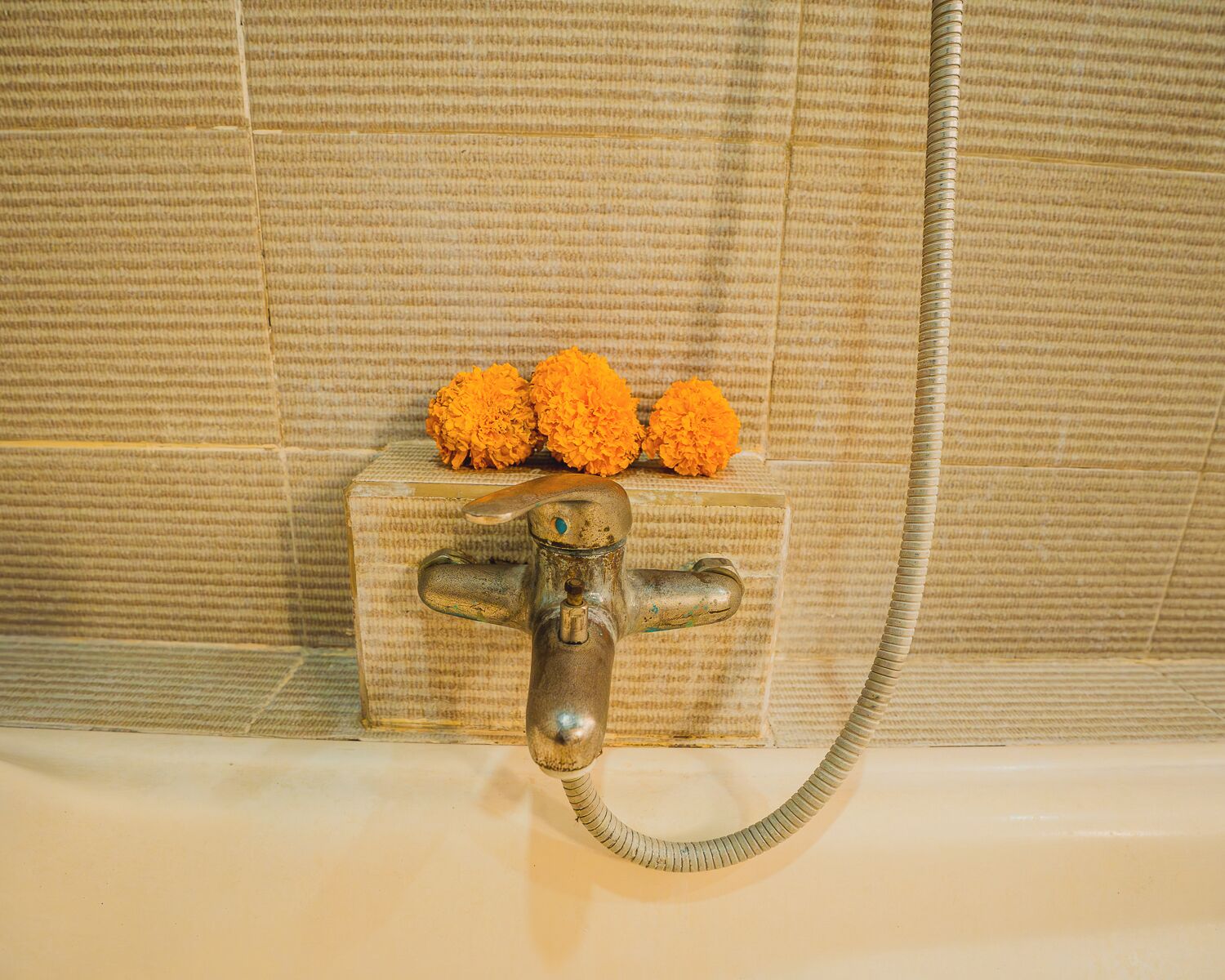 A bathroom with a shower, a metal faucet, and a hose.