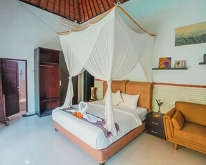 A bedroom with a four-poster bed, a nightstand, a sofa, and a painting on the wall.