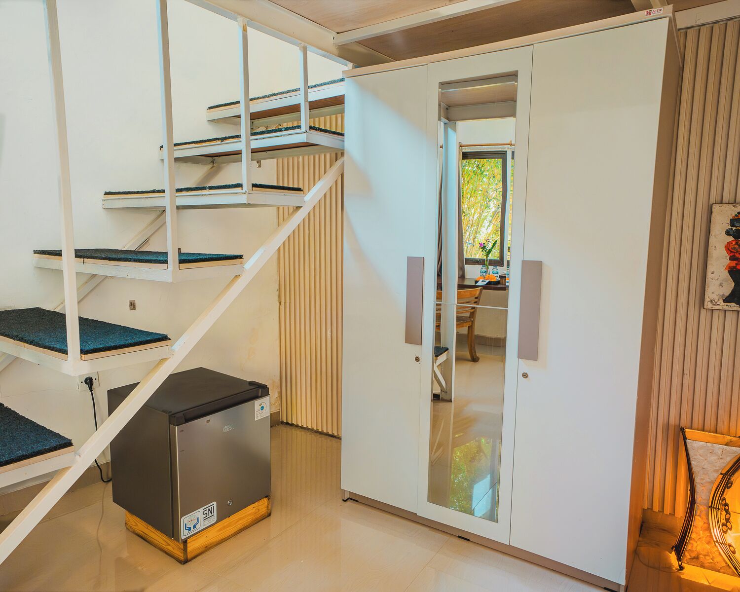 Un intérieur moderne avec un escalier, une petite cuisine et une porte donnant sur une autre pièce.
