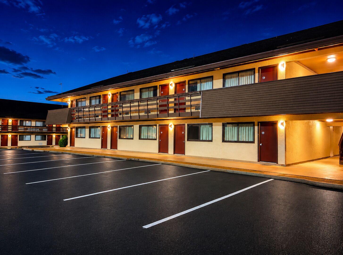 A multi-story motel with a parking lot, balconies, and a flat roof.
