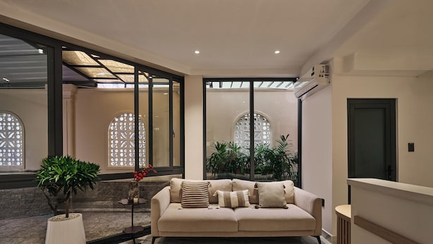 A modern living room with a beige sofa, a potted plant, and a marble floor. - Luckin Hotel (Ho Chi Minh City)