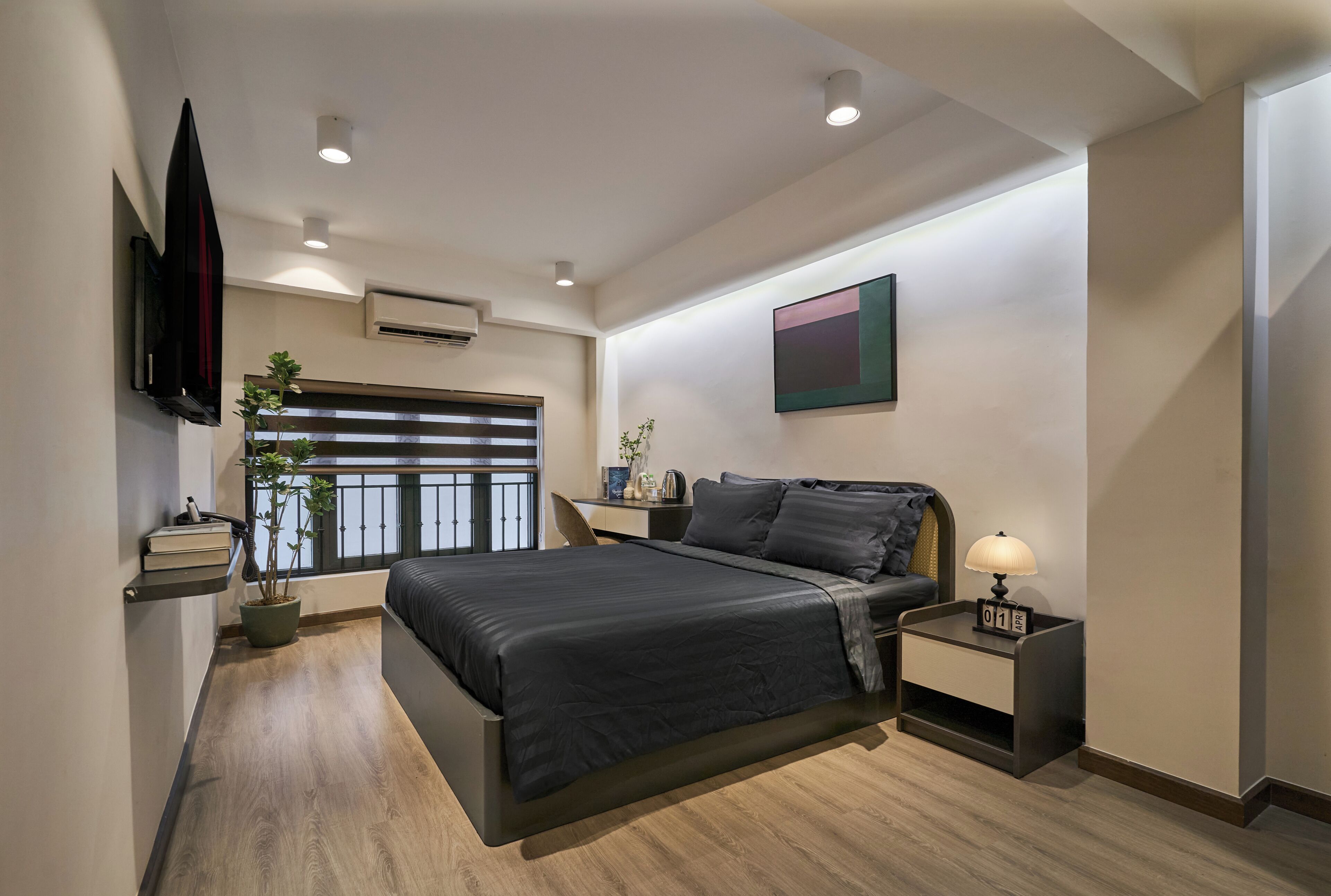 Un dormitorio moderno con cama, mesitas de noche, televisión, ventana con persianas y una planta en maceta.
