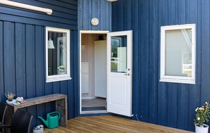 A wooden deck with a bench, a green watering can, and a potted plant. - Amazing home in Korsør with sauna (Korsør)