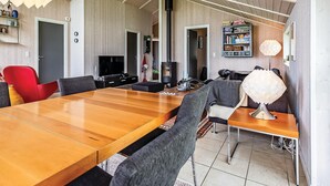 Ein moderner Essbereich mit einem Holztisch, Stühlen, einem Fernseher und einem Bücherregal.