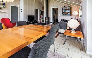 A modern dining area with a wooden table, chairs, a television, and a bookshelf. - Amazing home in Korsør with sauna (Korsør)