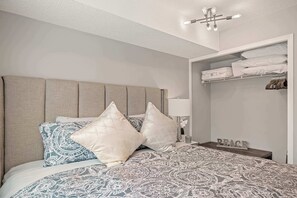 Ein Schlafzimmer mit Bett, Kissen, Nachttisch, Kleiderschrank und Deckenleuchte.