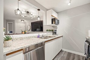 Eine moderne Küche mit Granit Arbeitsplatten, Edelstahlgeräten und Pendelleuchten.