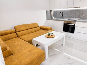 Uma sala de estar moderna com sofá, mesa de centro e área de cozinha com pia e forno.