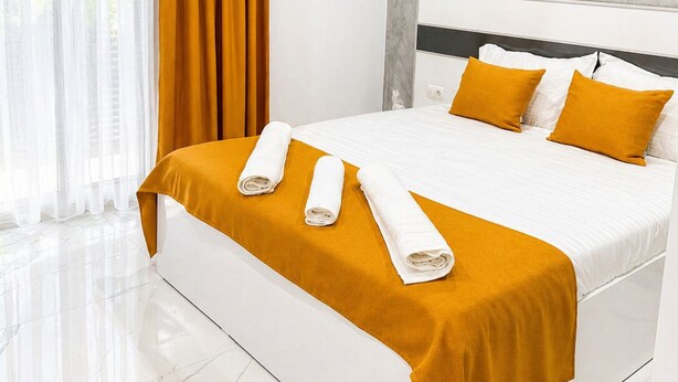 Een hotelkamer met een bed, witte gordijnen, een airconditioning en een marmeren vloer.