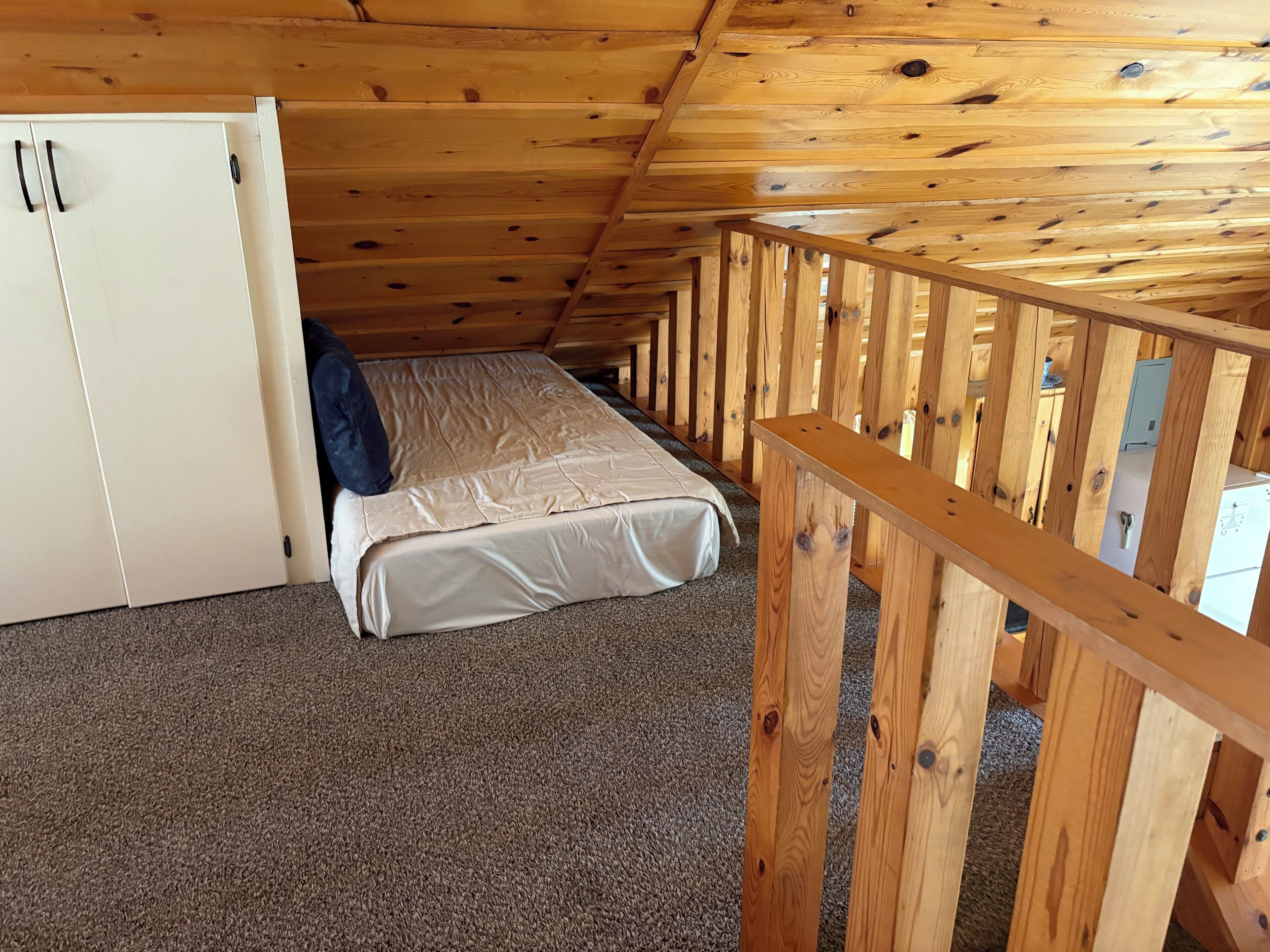 Ein Einzelzimmer mit einem Etagenbett, Holzboden und einem kleinen Schrank.