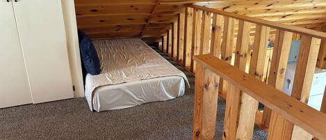 Ein Einzelzimmer mit einem Etagenbett, Holzboden und einem kleinen Schrank.