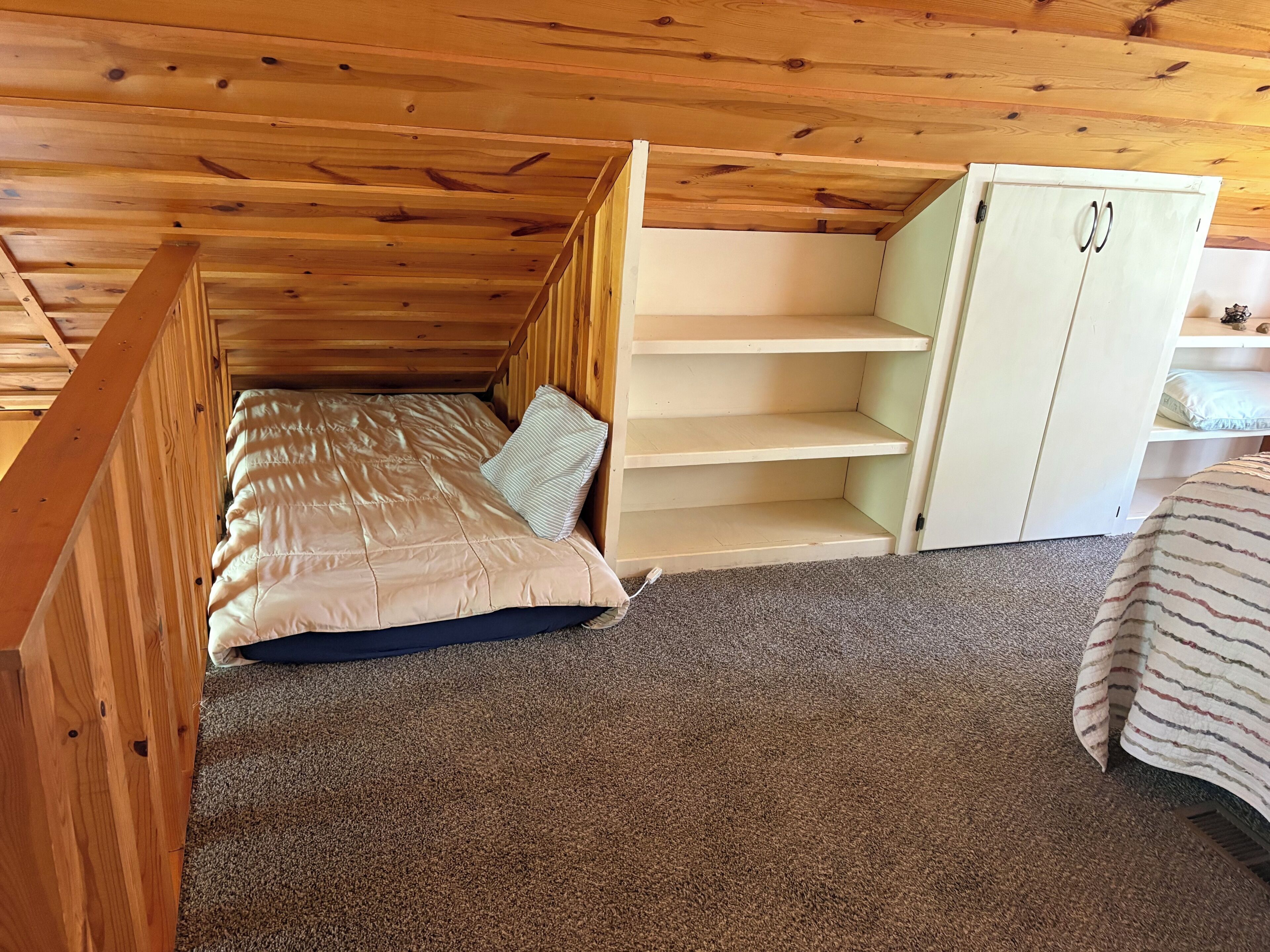 Une chambre avec un lit superposé, une armoire blanche et un sol recouvert de moquette.