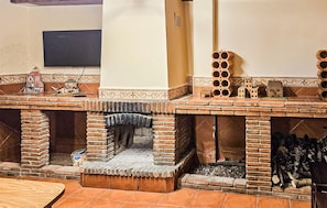 A brick fireplace with a chimney, a small table, and a decorative brick structure with multiple openings. - Vivienda Turistica La Gallomba (Rute)