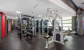 Ein Fitnessstudio mit verschiedenen Trainingsgeräten, darunter Kraftgeräte und Kurzhanteln.