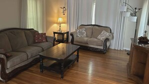 Ein Wohnzimmer mit einer Couch, einem Couchtisch, einer Lampe und einem Sessel.