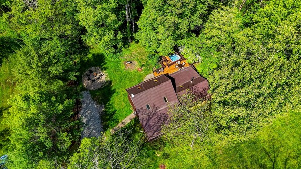 A house with a deck, surrounded by dense green forest.