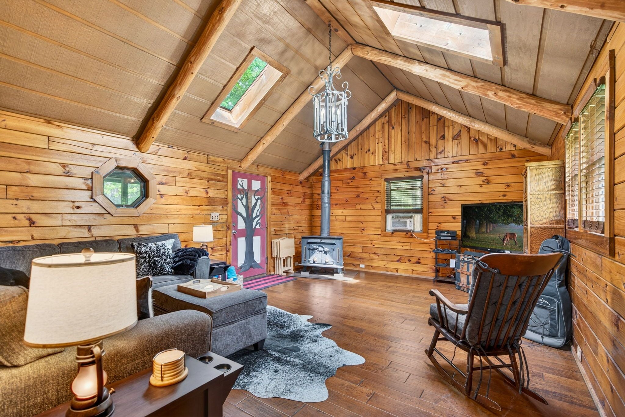 A cozy log cabin interior with a fireplace, seating area, and a television.