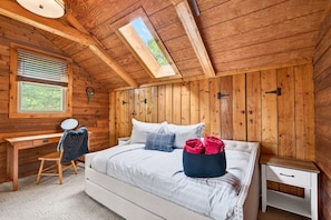 Una habitación con paneles de madera, una cama, un escritorio y una ventana.