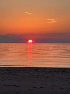 A sunset over a calm sea with a beach in the foreground. - Tulip Tree House in Shorewood-Tower Hills-Harbert, Michigan (Shorewood-Tower Hills-Harbert)