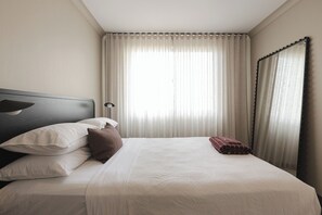 A neatly made bed with pillows, a bedside lamp, and a window with curtains. - The Cabbage Palm | Coastal Escape |
150m from Kiama's Main Street (Kiama)