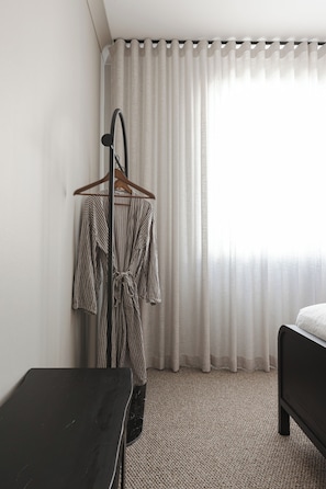 A hotel room with a bed, a wooden hanger with a striped robe, a black table, and a window with sheer curtains. - The Cabbage Palm | Coastal Escape |
150m from Kiama's Main Street (Kiama)