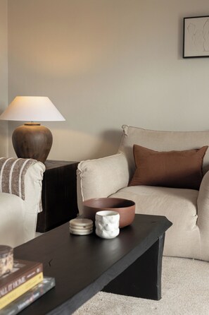 A living room with a sofa, a coffee table, a lamp, and a framed picture on the wall.