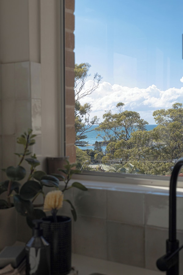 A window with a view of trees and the sea.