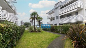 A modern residential building with balconies, a well-maintained lawn, and a paved pathway. - Maricel residence °swimming pool#modern° (Lido di Jesolo)