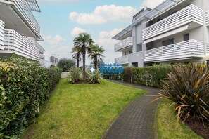 A modern residential building with balconies, a well-maintained lawn, and a paved pathway. - Maricel residence °swimming pool#modern° (Lido di Jesolo)