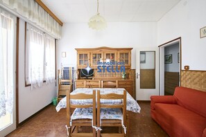 A room with a bunk bed, a red sofa, a wooden cabinet, and a television. - Accogliente # trilocale 100mt from the sea# (Jesolo)