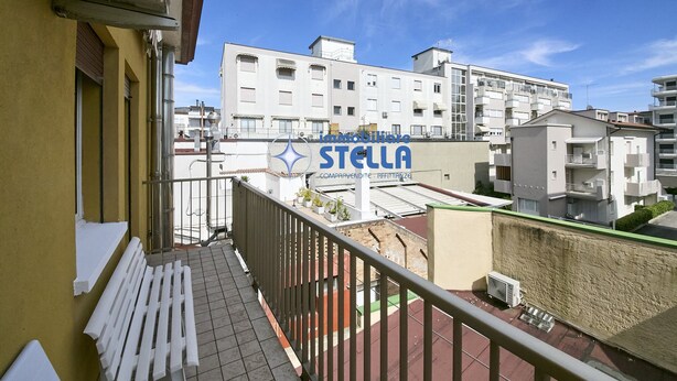 A balcony with a railing, a white bench, and a sign for 'Imattieri STELLA' in the background. - Accogliente # trilocale 100mt from the sea# (Jesolo)