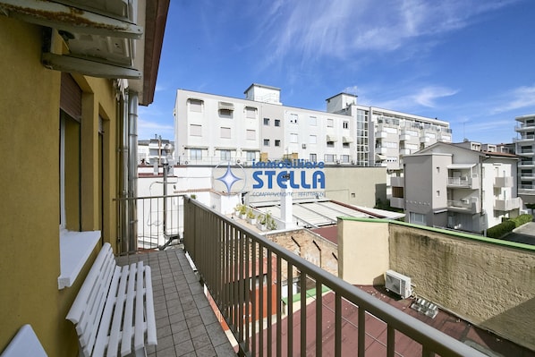 A balcony with a railing, a white bench, and a sign for 'Imattieri STELLA' in the background. - Accogliente # trilocale 100mt from the sea# (Jesolo)